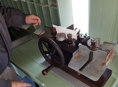 Early machine cancel. The covers were fed into it from the left side; cranking the hand wheel fed them through the machine, where they were cancelled and deposited into the collection tray on the right side.